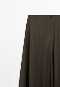 Pantalon taille haute marron foncé à la texture lisse, doté d'une fermeture éclair cachée à l'arrière et d'une coupe à jambes larges.