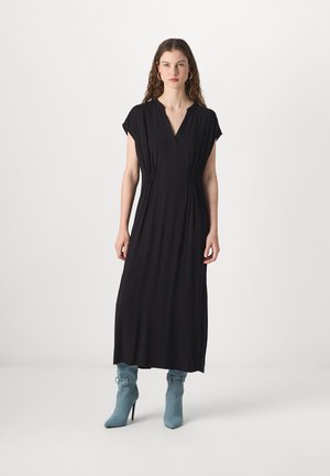 Black, knee-length dress with short cap sleeves and a V-neck, featuring gathered side details. Paired with light blue, pointed-toe ankle boots.