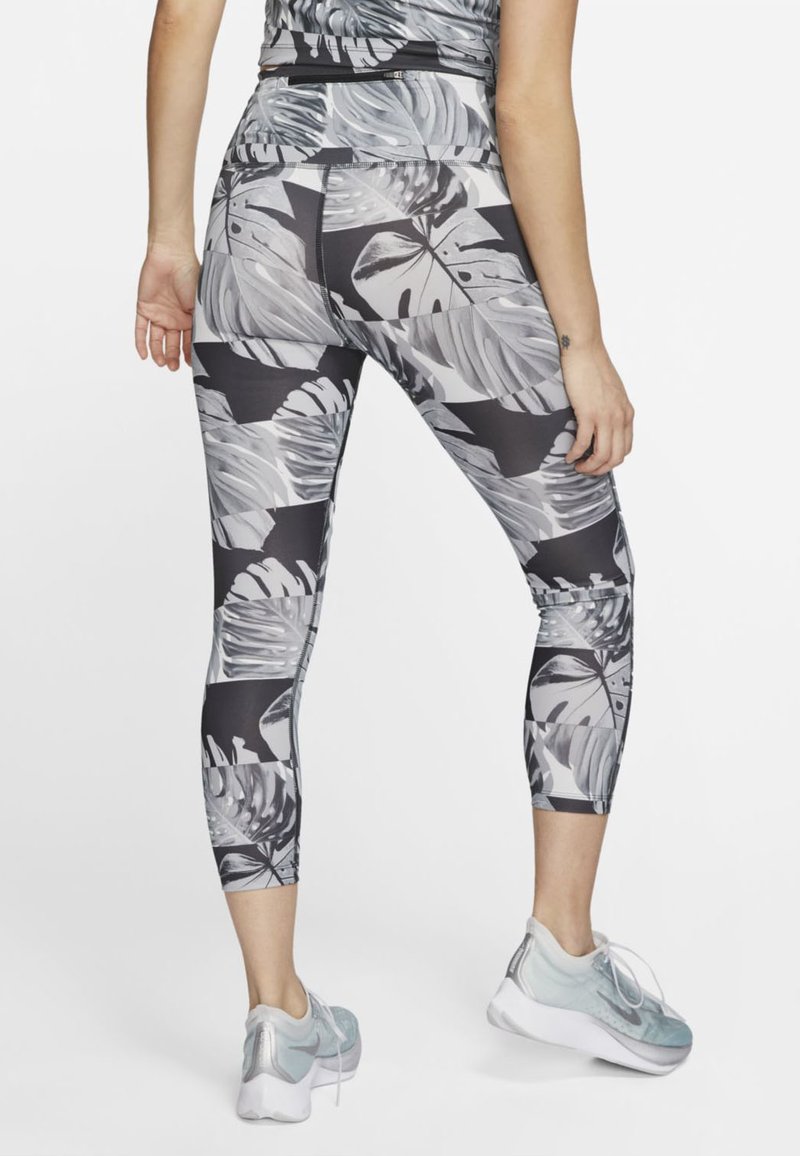 Dopasowane legginsy o długości capri w czarno-białym wzorze tropikalnych liści. Wykonane z elastycznego materiału o gładkiej fakturze, idealne do aktywności fizycznej.