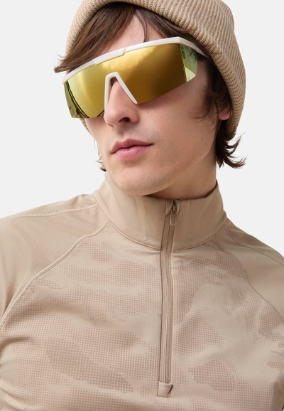 Beige Viertel-Reißverschluss-Oberteil mit strukturiertem Muster, kombiniert mit übergroßen weißen Sonnenbrillen mit gold verspiegelt Gläsern.