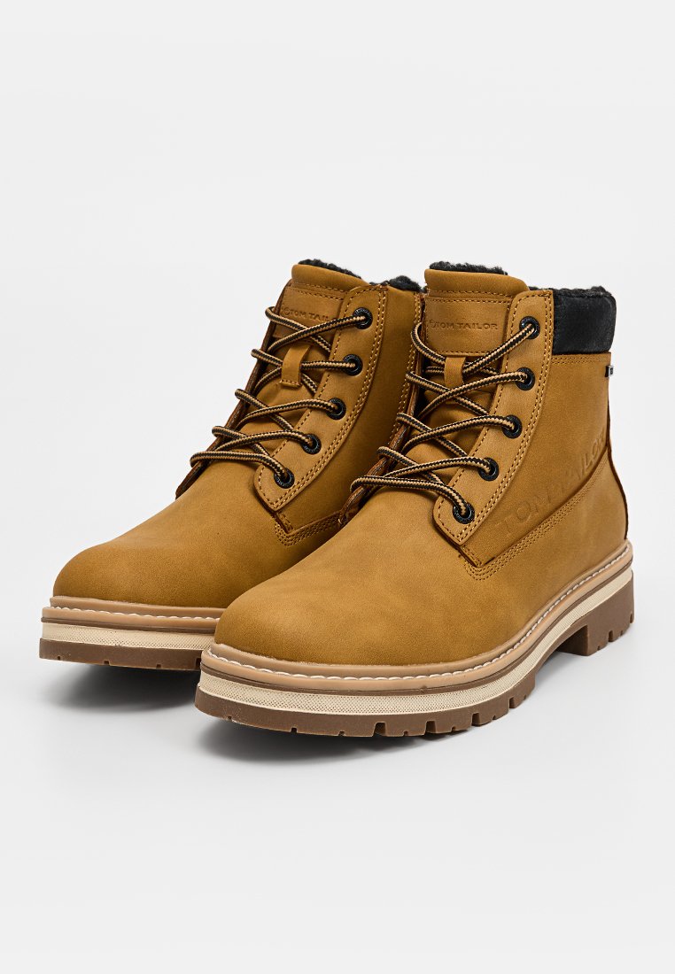 Leren enkellaarsjes in tan met een zwarte stoffen kraag, ronde veters en een getextureerde rubberen zool. Bevat een gestikte beige tussenzool en een logo-detail.