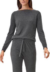 Maglione grigio a maglia con scollatura ampia e maniche lunghe, abbinato a pantaloni grigi con cordoncino. Texture morbida e vestibilità rilassata.