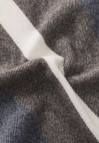 Grijs en marineblauw gestreepte stof met een witte accent. De textuur is zacht met een ribbelpatroon, wat een warme, gezellige uitstraling geeft.