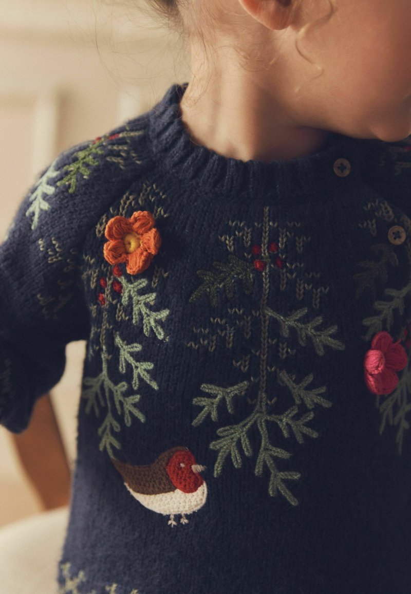 Marineblauer Strickpullover mit floraler Stickerei, versehen mit einem Vogel, orangefarbenen Blütenakzenten und grünen Blättermustern. Dekorative Holzknöpfe sind enthalten.