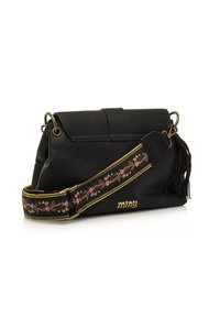 Borsa nera con chiusura a pattina, dotata di una tracolla decorativa con ricami floreali e un accento con nappina. Dettagli in hardware dorato.