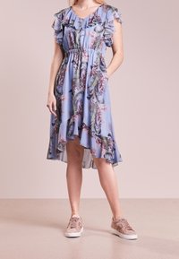 Sininen, kukkakuosiset mekko, jossa on röyhelöhiha, vyötärö on kireä ja helma on epäsymmetrinen. Yhdistetty vaaleanpunaisiin tennareihin.