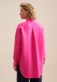 Fuchsia gestreepte shirt met een ontspannen pasvorm, lange mouwen, knoopmanchetten en een gesplitste rugplooien. Soepele textuur met verticale witte strepen.