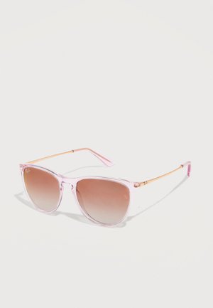 Transparent pink-framed sunglasses with light brown gradient lenses and thin gold temples resting on a white surface.