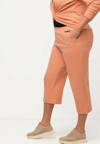 Peach-farvede cropped sweatpants med sidelommer, lavet af blødt stof, der har en afslappet pasform og enkle, rene linjer.