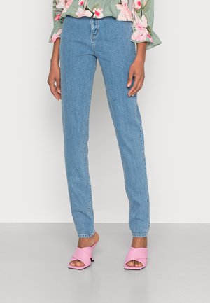 Calças de ganga azul claro com um corte reto, apresentando uma textura subtil. Combinadas com mules rosa de tiras cruzadas sobre um fundo neutro.