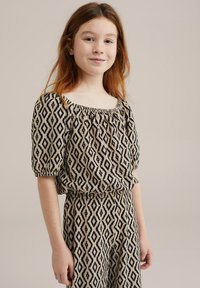 Halenka s krátkým rukávem a čtvercovým výstřihem a odpovídající kalhoty v béžové barvě s černým diamantovým vzorem. Texturovaná látka s nařasením na výstřihu a pase.