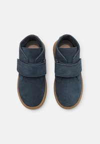 Granatowe zamszowe botki za kostkę z szerokim paskiem na rzep, tanowymi gumowymi podeszwami i zaokrąglonym czubkiem. Idealne na codzienne noszenie.