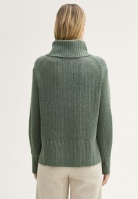 Zielony sweter z dzianiny z wysokim kołnierzem, z teksturowanym wzorem w prążki, akcentami splotu warkocza oraz luźnym krojem.