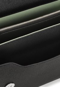 Borsa nera in pelle texture con un interno liscio, dotata di una zip e di un accento argentato. Progettata per l'organizzazione con più scomparti.