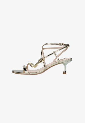 Sandalo dorato con cinturini, tacco kitten sottile, chiusure con fibbia e dettaglio decorativo a catena lungo la fascia frontale.