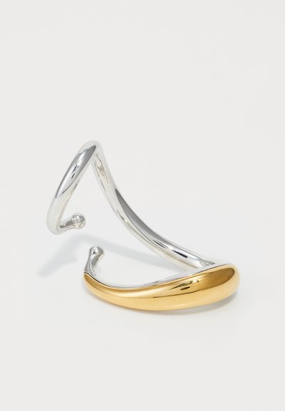 Armband aus Silber- und Goldfarbenem Metall mit gedrehter Gestaltung; glatte, glänzende Oberfläche mit abgerundeten Enden und fließender Form.