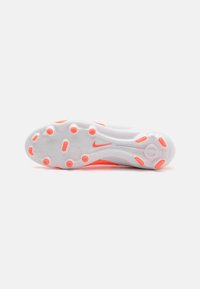 Valkoinen urheilujalkine, jossa on teksturoitu pohja, oranssit yksityiskohdat ja pyöreät nappulakuvioinnit pidon parantamiseksi. Nike-logo sivussa.
