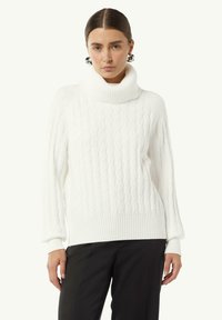 Weißer Kabelstrickpullover mit hohem, geripptem Rollkragen und gerippten Bündchen. Er zeichnet sich durch eine lockere Passform und ein strukturiertes Muster aus.