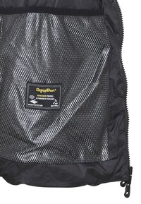 Interno di una giacca nera isolata con fodera in rete, dotata di un'etichetta che indica protezione dall'acqua e traspirabilità. Presente una chiusura con zip.