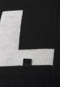Tissu tricoté en noir et blanc avec un grand motif géométrique et une petite étiquette carrée noire portant l'inscription « KARL LAGERFELD ».