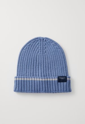 Hellblaue, gestrickte Mütze mit geripptem Muster, kontrastierender cremefarbener Streifen am Saum und einem dunklen Etikett mit weißem Text.