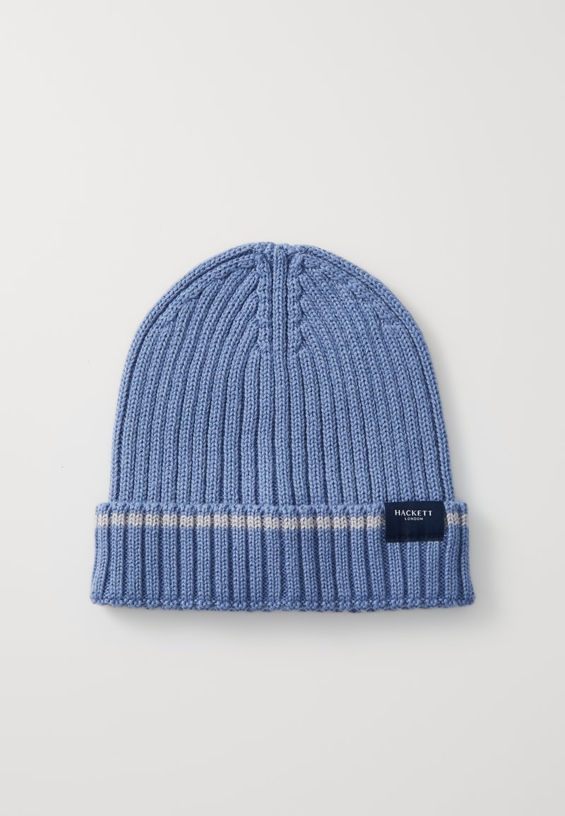 Light blue knitted beanie with ribbed texture, contrasting cream stripe on the cuff, and a dark label with white text.