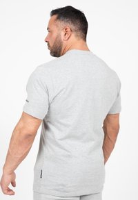 Grijze katoenen t-shirt met korte mouwen en een ronde halslijn, met zijnaden. Subtiele textuur; label zichtbaar aan de onderkant.