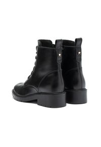 Botas de tobillo de cuero negro con punta redondeada, cordones en la parte delantera y suela de goma texturizada. Presentan una lengüeta y detalles de costura distintivos.