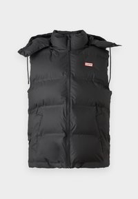Melnā pūkainā veste ar augstu apkakli, ar rāvējslēdzēju, regulējamu kapuci, divām sānu kabatām un nelielu sarkanu un baltu logotipu uz krūts.