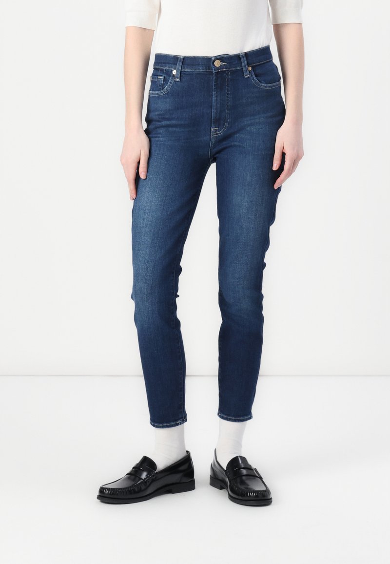 Jeans i mørkeblått denim, slim-fit design med mid-rise liv, som har fem lommer, knappelukking og detaljer i gullfarge.