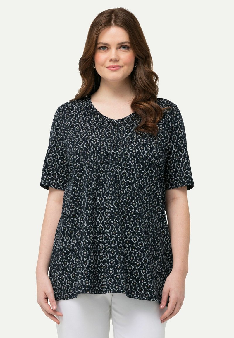 Top de estampado floral en azul marino con mangas cortas y cuello redondeado. Tejido ligero con corte holgado y un sutil patrón texturizado.