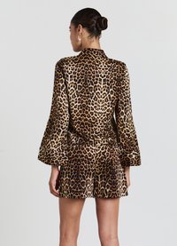 Ensemble à imprimé léopard comprenant des manches longues évasées et un short, fabriqué à partir d'un tissu lisse et à motifs dans des nuances de marron et de noir.