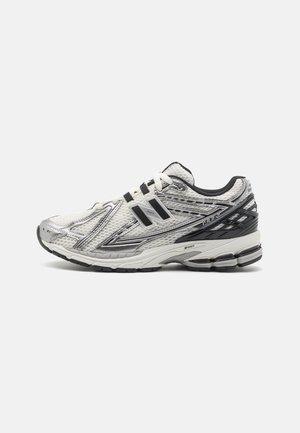 Sapatos de corrida masculinos em malha branca com detalhes pretos, apresentando uma sola acolchoada, design de atacadores e uma superfície texturizada para melhor aderência.