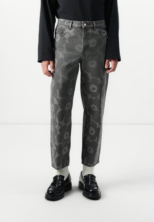 Gray floral-patterned denim jeans with a relaxed fit, five pockets, and a button closure. Worn with black loafers and white socks.