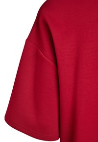 Červené bavlnené tričko s uvoľneným strihom a širokými rukávmi. Hladká textúra bez viditeľných vzorov alebo hardvérových detailov.