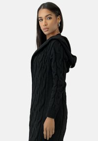 Schwarzer Kapuzencardigan aus strukturiertem Strick mit einem Kabelmuster, ausgestattet mit langen Ärmeln und einer locker sitzenden Passform.