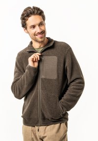 Brown fleece jacket with a high collar, zippered chest pocket, and side pockets. Features soft, textured material and a relaxed fit.