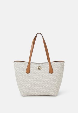Beżowa torba typu tote Michael Kors z brązowymi skórzanymi uchwytami i powtarzającym się wzorem logo MK, centralne złote godło MK z przodu.