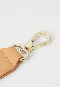 Μπεζ δερμάτινη ζώνη με μεταλλικό κλιπ σε χρυσό τόνο. Διαθέτει καμπύλη πρόσδεση στυλ καραμπίνας με λεπτομέρεια λογοτύπου. Λείο υλικό, ελάχιστη ραφή.