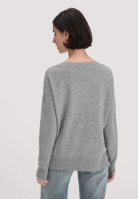 Grau gestrickter Pullover mit lockerer Passform, weitem Ausschnitt und gerippten Bündchen und Saum. Weiche Textur und minimalistisches Design, von hinten gezeigt.