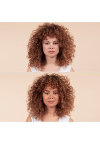 Ritratto di una persona con capelli ricci scuri e boccoli voluminosi e texturizzati. La persona ha la pelle chiara e indossa una maglietta bianca.