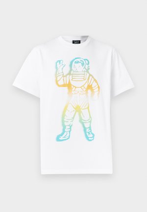 Balts T krekls ar krāsainu svītrainu grafiku, attēlojot viļņojošu astronautu kosmosa tērpā, kas centrēts priekšpusē.