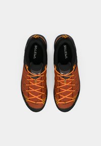 Oranje mesh sportchoenen met zwarte accenten, voorzien van een textuur oppervlakte, oranje veters en een flexibele rubberen zool.