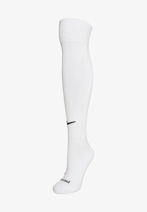 Witte sportkousen tot de knie, gemaakt van een gladde, rekbare stof. Bevat een zwart Nike-logo nabij de bovenkant en een geribbelde manchette.