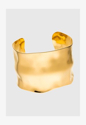 Pulseira de pulso dourada com um design ondulado, superfície lisa e refletora, forma de extremidade aberta e bordas arredondadas, formando uma silhueta ousada.
