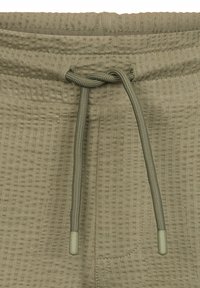 Joggers verde oliva in tessuto testurizzato; presentano un cordino con estremità coordinate e una tasca laterale per praticità.