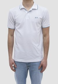 Polo shirt bianco a maniche corte, con colletto classico, accenti blu sul colletto e sui bordi delle maniche, con un piccolo logo sul lato sinistro del petto.