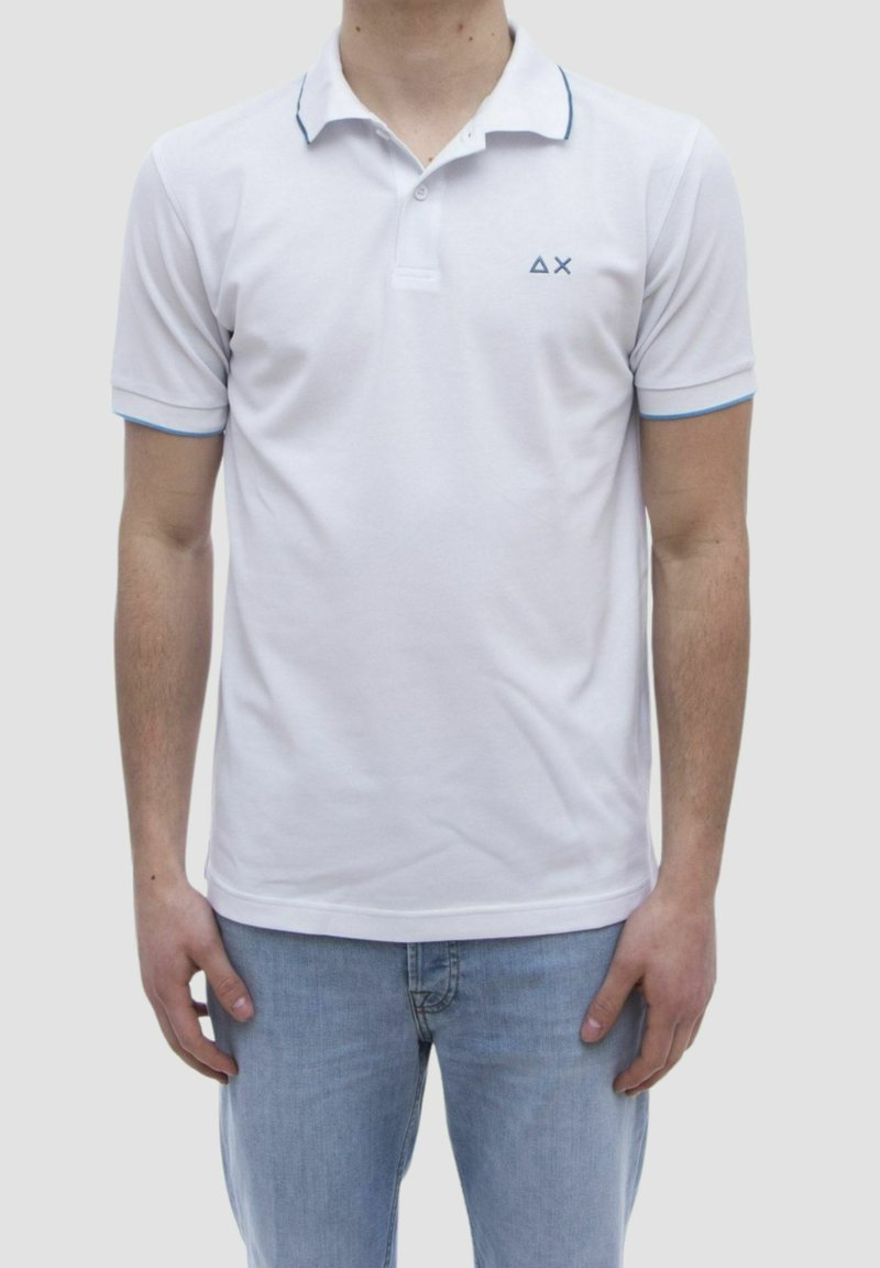 Polo shirt bianco a maniche corte, con colletto classico, accenti blu sul colletto e sui bordi delle maniche, con un piccolo logo sul lato sinistro del petto.