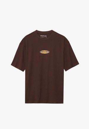 T-shirt en coton marron avec un col rond, des manches courtes et un logo graphique en orange et jaune sur la poitrine. Texture lisse.