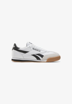 Sneaker blanche avec des accents noirs et un logo Reebok. Présente un matériau en cuir et en daim, un design de lacets plats, une semelle extérieure en caoutchouc gomme et une silhouette classique.